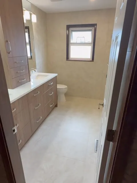 A finished bathroom renovation seen from the hallway — full vanity wall and window.
